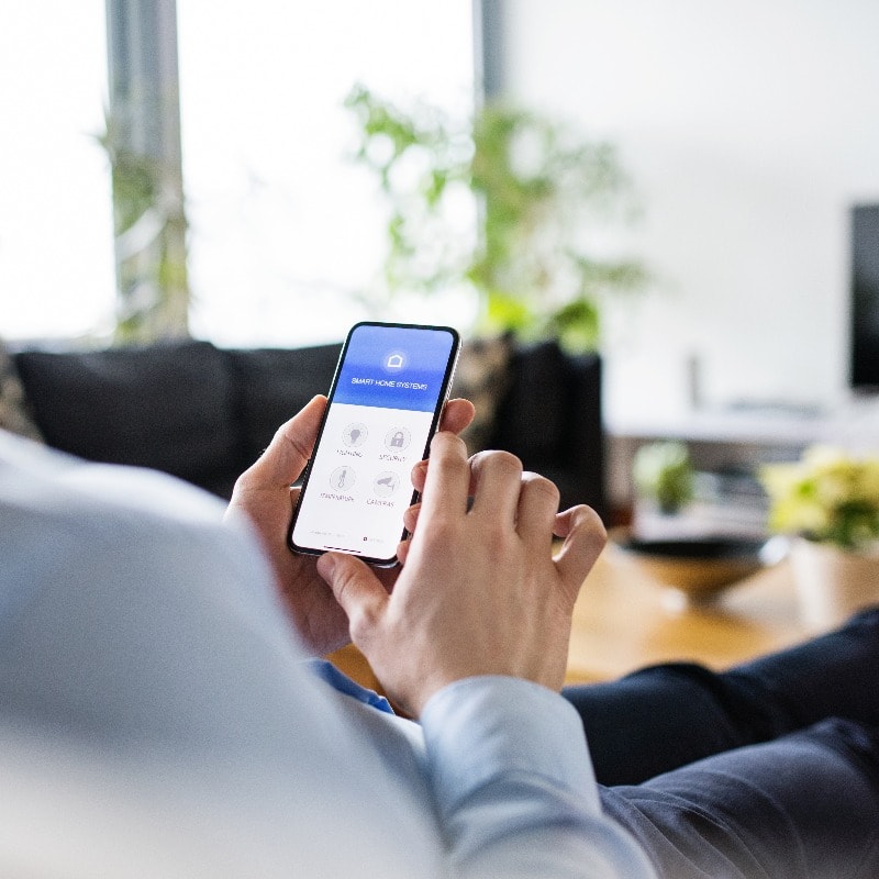 A man holding a smartphone with smart home screen.